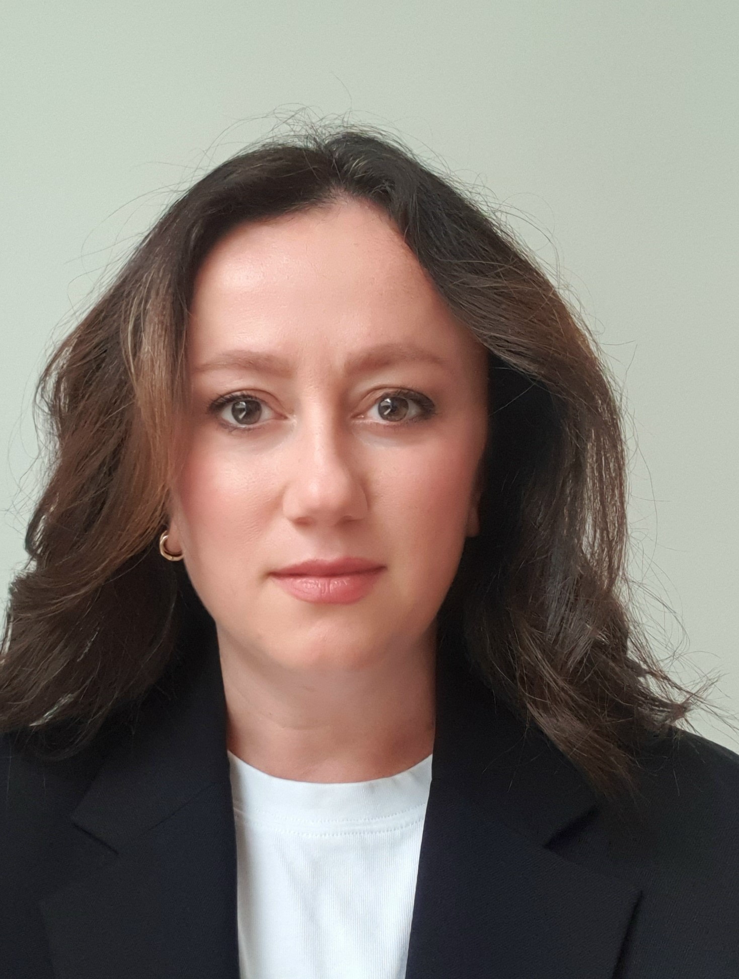 A portrait photo of Dr. Zeliha Guler in a black jacket and white t-shirt